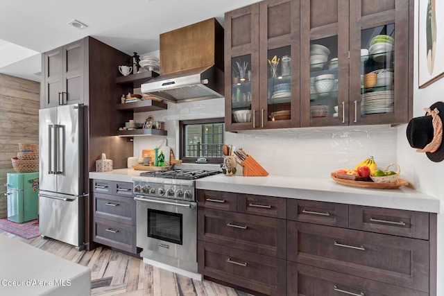 kitchen featuring dark brown cabinets, ventilation hood, high end appliances, and light countertops
