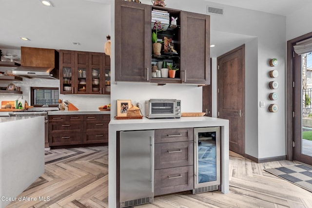 bar featuring exhaust hood, a toaster, appliances with stainless steel finishes, visible vents, and wine cooler