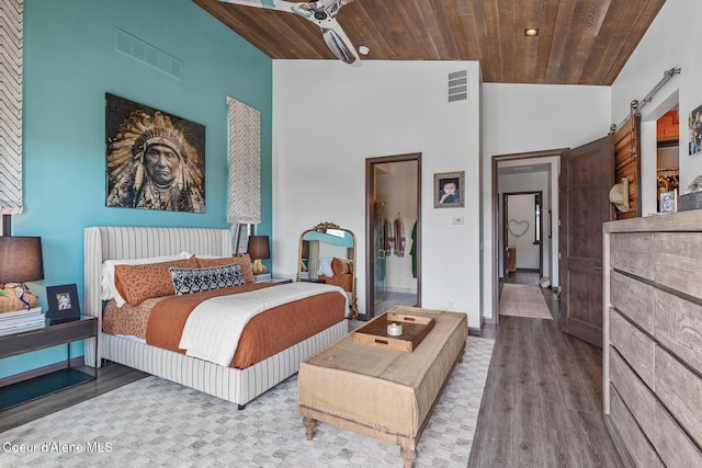 bedroom with a barn door, visible vents, wood finished floors, and wooden ceiling
