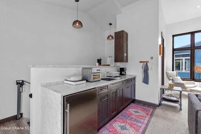 interior space featuring wood finished floors, decorative light fixtures, stainless steel refrigerator, a sink, and high vaulted ceiling