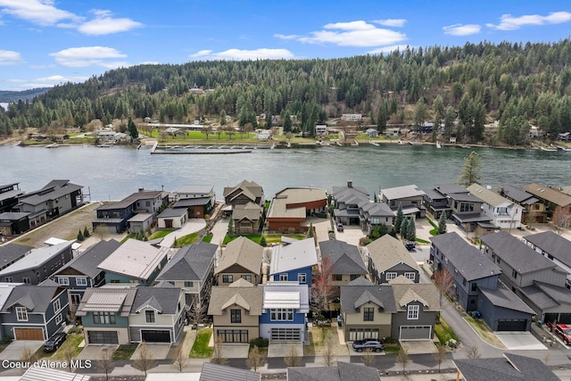 drone / aerial view featuring a water view, a view of trees, and a residential view