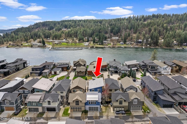 aerial view featuring a wooded view, a water view, and a residential view