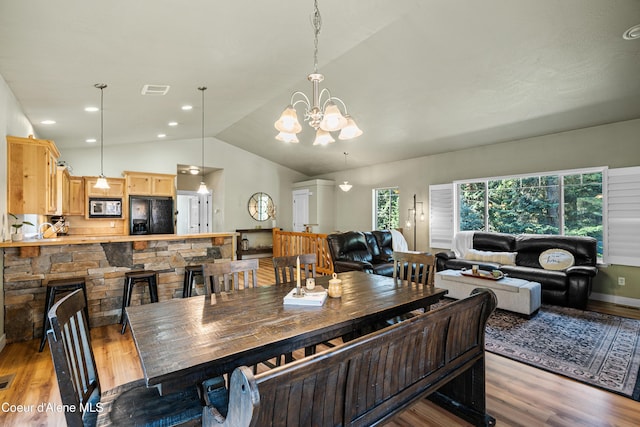 dining area with light wood-style floors, plenty of natural light, lofted ceiling, and a notable chandelier