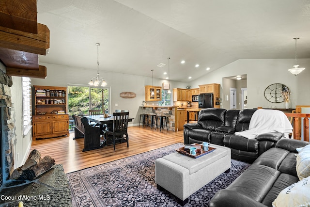 living room with lofted ceiling, light wood finished floors, and a notable chandelier