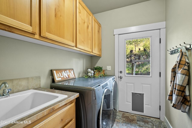 washroom with a sink, separate washer and dryer, stone finish flooring, and cabinet space