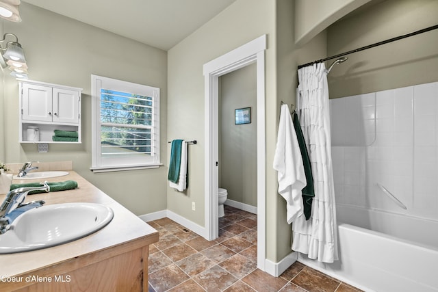 full bath with baseboards, a sink, double vanity, and toilet