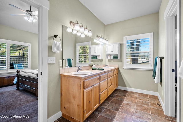 ensuite bathroom with a sink, baseboards, ceiling fan, and double vanity