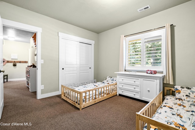bedroom with baseboards, a closet, dark colored carpet, and visible vents