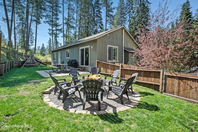 back of property with a lawn, a fenced backyard, an outdoor fire pit, and a patio area