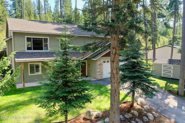 view of front of property featuring a front lawn, roof with shingles, and a storage unit