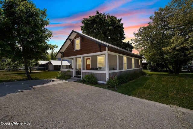 bungalow featuring covered porch and a yard