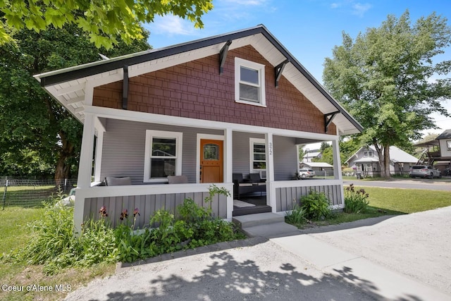 bungalow-style home with covered porch and fence