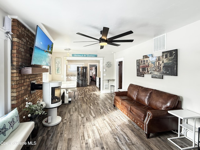 living room with a fireplace, visible vents, ceiling fan, and wood-type flooring