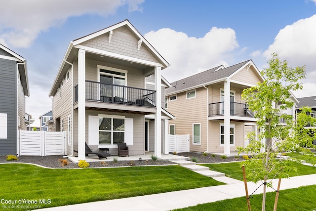 view of front facade with fence, a patio area, a front lawn, and a balcony