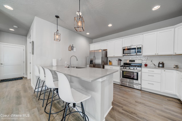 kitchen with a sink, appliances with stainless steel finishes, a kitchen breakfast bar, and light wood finished floors