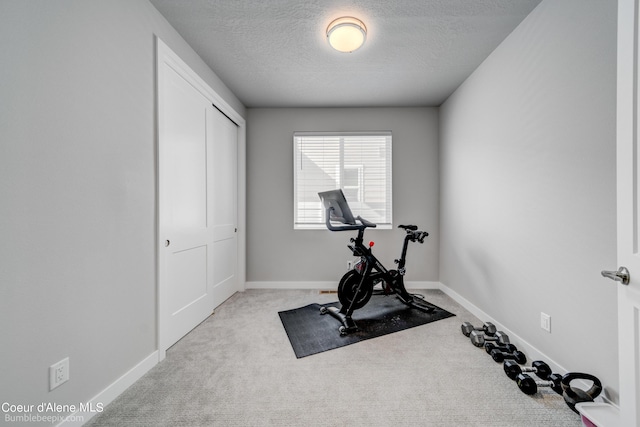 workout area with a textured ceiling, baseboards, and carpet