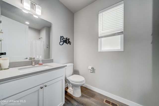 bathroom with a shower with curtain, visible vents, wood finished floors, baseboards, and toilet