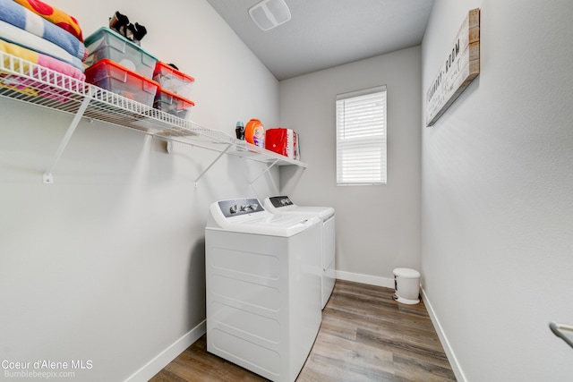 washroom with baseboards, laundry area, washing machine and dryer, and wood finished floors