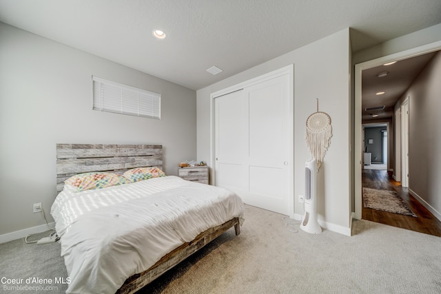 bedroom with a closet, recessed lighting, carpet, and baseboards