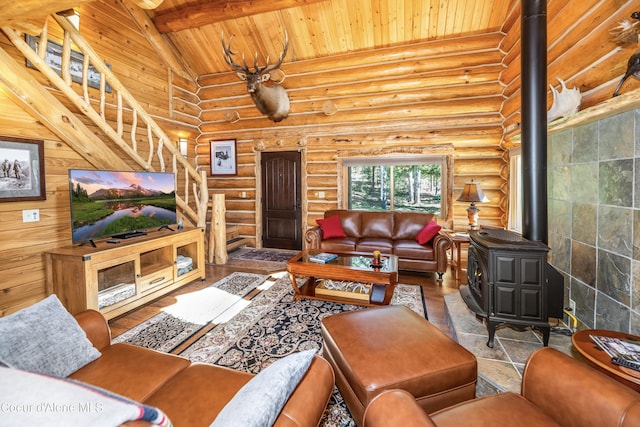 living room featuring a wood stove, log walls, stairs, beam ceiling, and wood ceiling