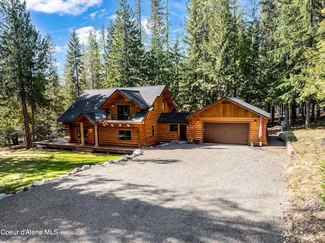log-style house with log exterior, an attached garage, driveway, and a front lawn