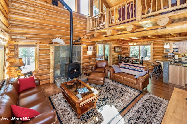 living room featuring log walls, a wood stove, and hardwood / wood-style floors