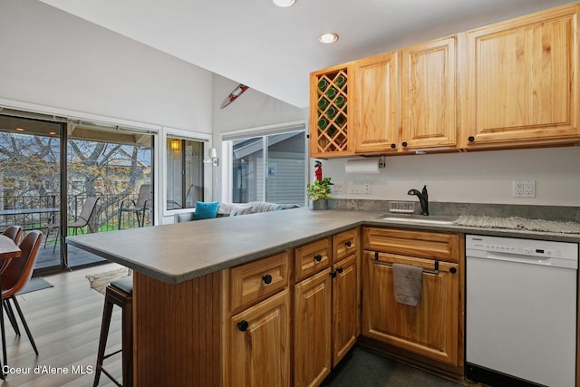 kitchen featuring a sink, dishwasher, recessed lighting, a peninsula, and dark wood-style floors
