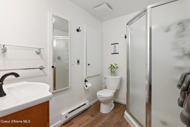 full bathroom with vanity, toilet, wood finished floors, a baseboard heating unit, and a stall shower
