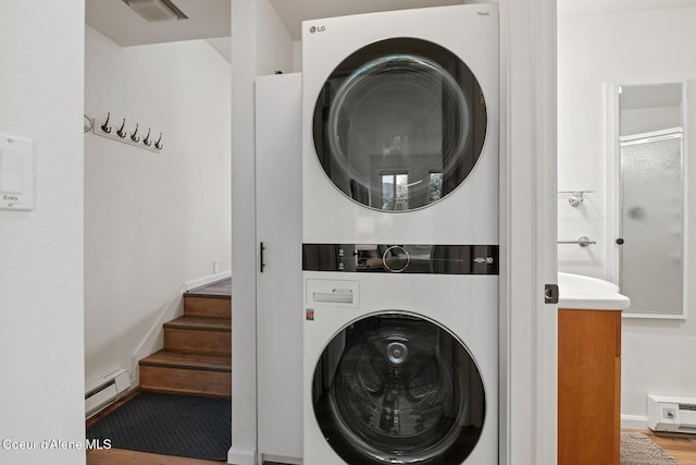 laundry area featuring laundry area, a baseboard radiator, and stacked washing maching and dryer