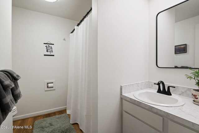bathroom featuring vanity, baseboards, wood finished floors, and a shower with shower curtain