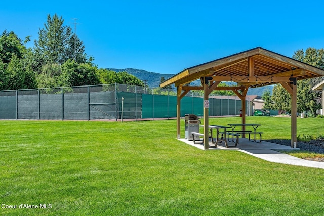 view of community with a gazebo, fence, a mountain view, a yard, and a tennis court