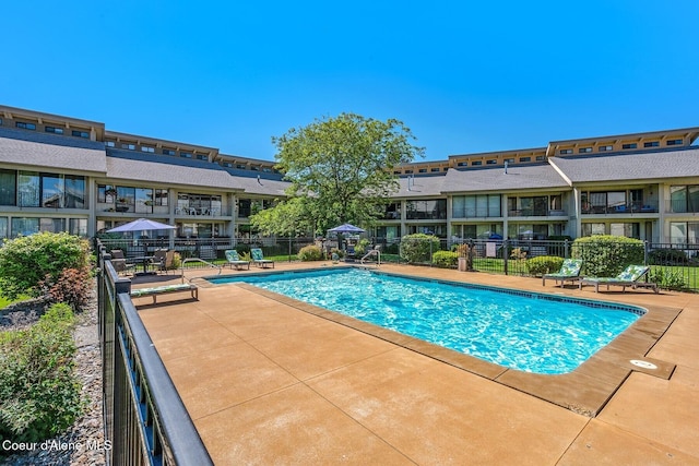 community pool with a patio and fence
