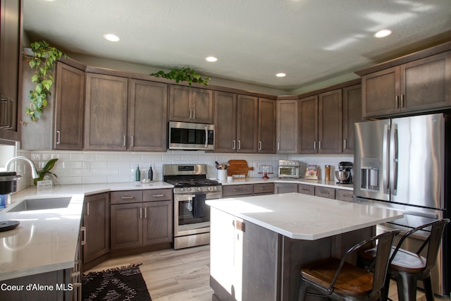 1733 N Minam Loop, Post Falls, ID 83854 - kitchen featuring a breakfast bar area, decorative backsplash, a sink, light wood-style floors, and stainless steel appliances