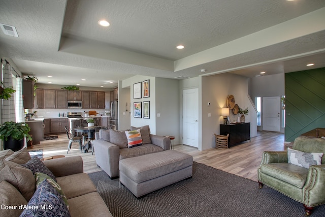1733 N Minam Loop, Post Falls, ID 83854 - living area with recessed lighting, light wood finished floors, visible vents, a raised ceiling, and a textured ceiling