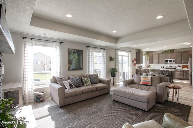 1733 N Minam Loop, Post Falls, ID 83854 - living area with a textured ceiling, recessed lighting, light wood-style flooring, and a tray ceiling
