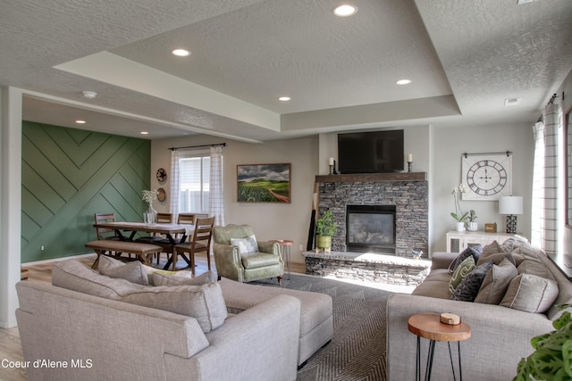 1733 N Minam Loop, Post Falls, ID 83854 - living area featuring recessed lighting, a stone fireplace, light wood-type flooring, a raised ceiling, and a textured ceiling