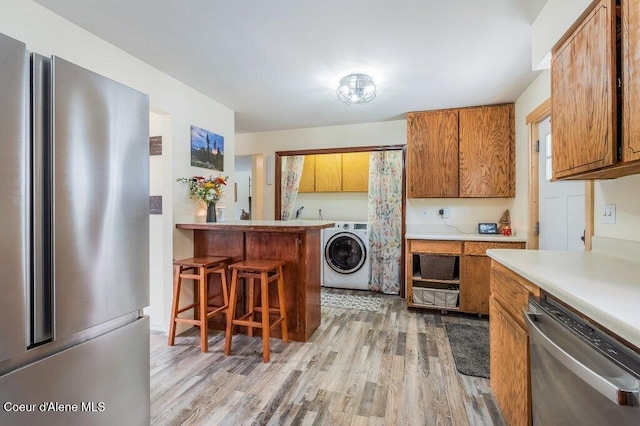820 Plum Ln, Saint Maries, ID 83861 - kitchen featuring a kitchen bar, washer / clothes dryer, brown cabinets, light wood-style floors, and stainless steel appliances