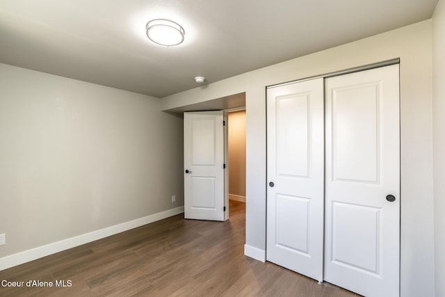 unfurnished bedroom featuring dark wood-style flooring, baseboards, and a closet