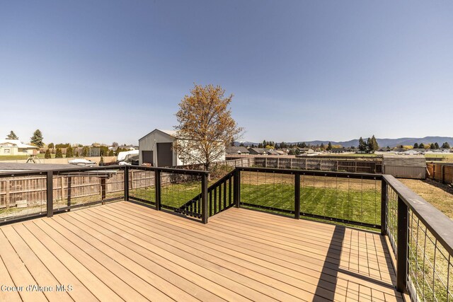 wooden terrace with a fenced backyard, a mountain view, an outdoor structure, and a yard