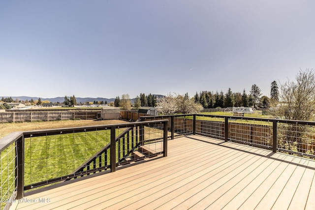 wooden terrace with a fenced backyard, a mountain view, and a yard