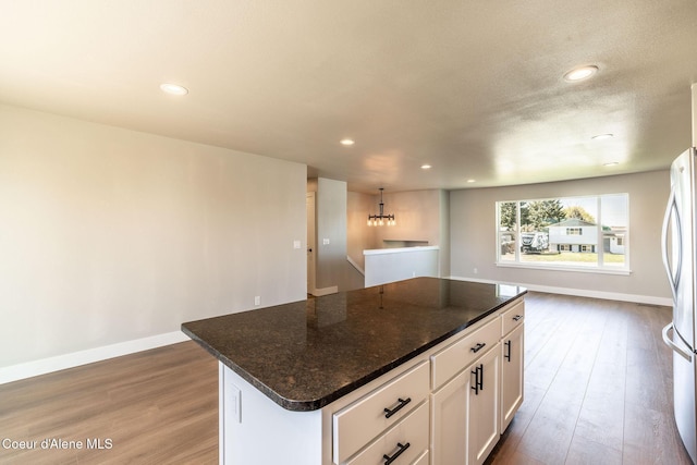 kitchen with recessed lighting, a kitchen island, wood finished floors, and white cabinets