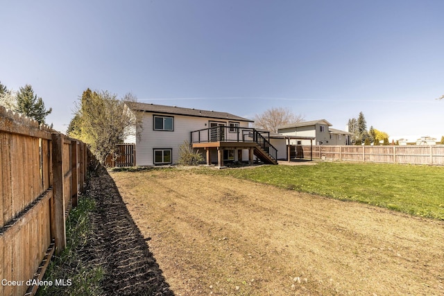 back of property with stairs, a fenced backyard, a lawn, and a deck
