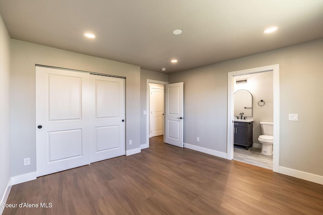 unfurnished bedroom featuring a closet, wood finished floors, baseboards, recessed lighting, and a sink