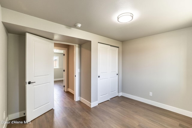 unfurnished bedroom with baseboards, dark wood finished floors, and a closet