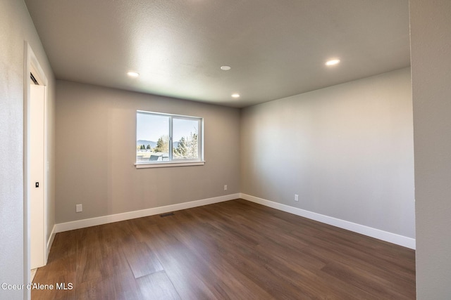 empty room featuring recessed lighting, dark wood-style flooring, baseboards, and visible vents