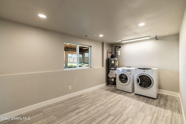 clothes washing area with water heater, baseboards, recessed lighting, and washer and dryer