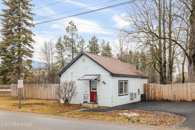 bungalow with board and batten siding, fence, and metal roof
