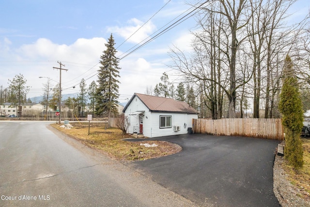 exterior space featuring fence, metal roof, and driveway