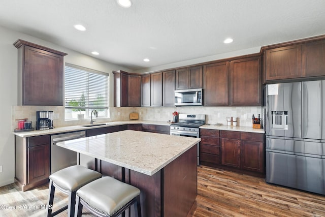 1622 N Minam Loop, Post Falls, ID 83854 - kitchen featuring stainless steel appliances, a sink, a center island, wood finished floors, and backsplash