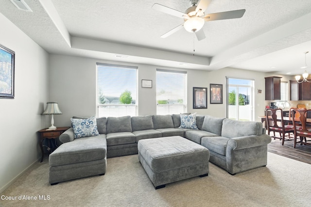 1622 N Minam Loop, Post Falls, ID 83854 - carpeted living area featuring a ceiling fan, a chandelier, a textured ceiling, baseboards, and a raised ceiling
